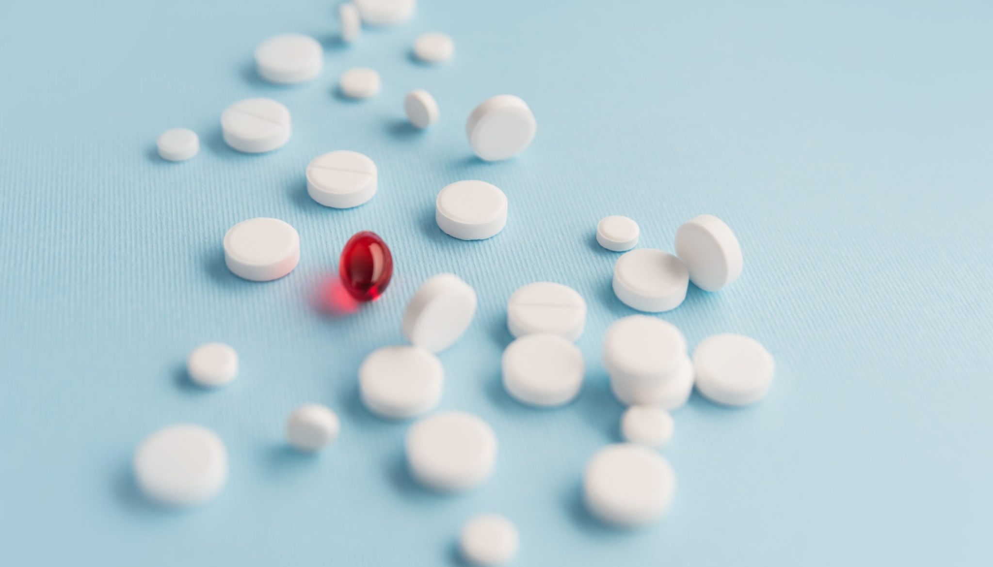 Close up of white tablets with one red capsule isolated