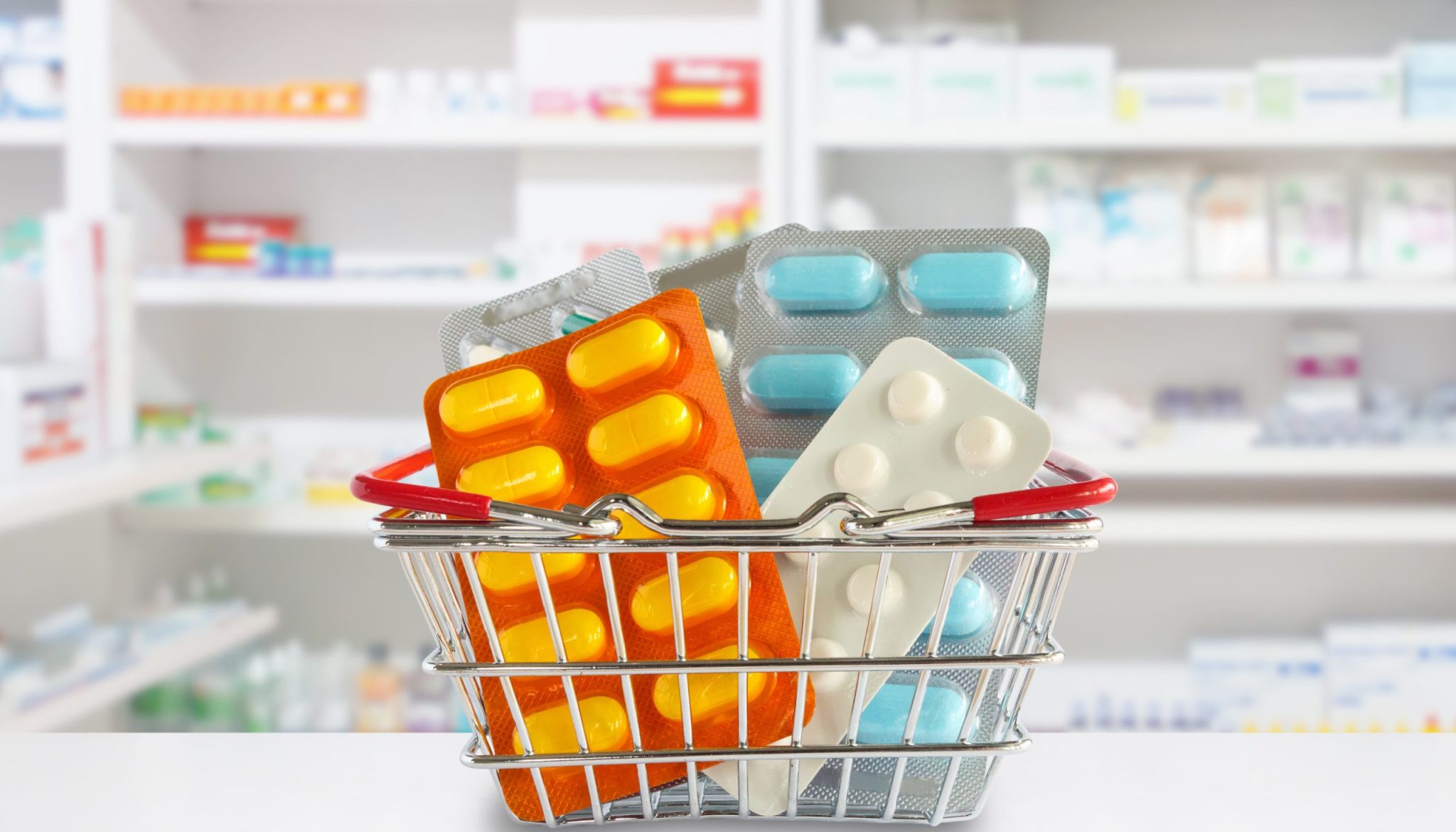 Medicine pills package in shopping basket with pharmacy drugstore shelves blur background