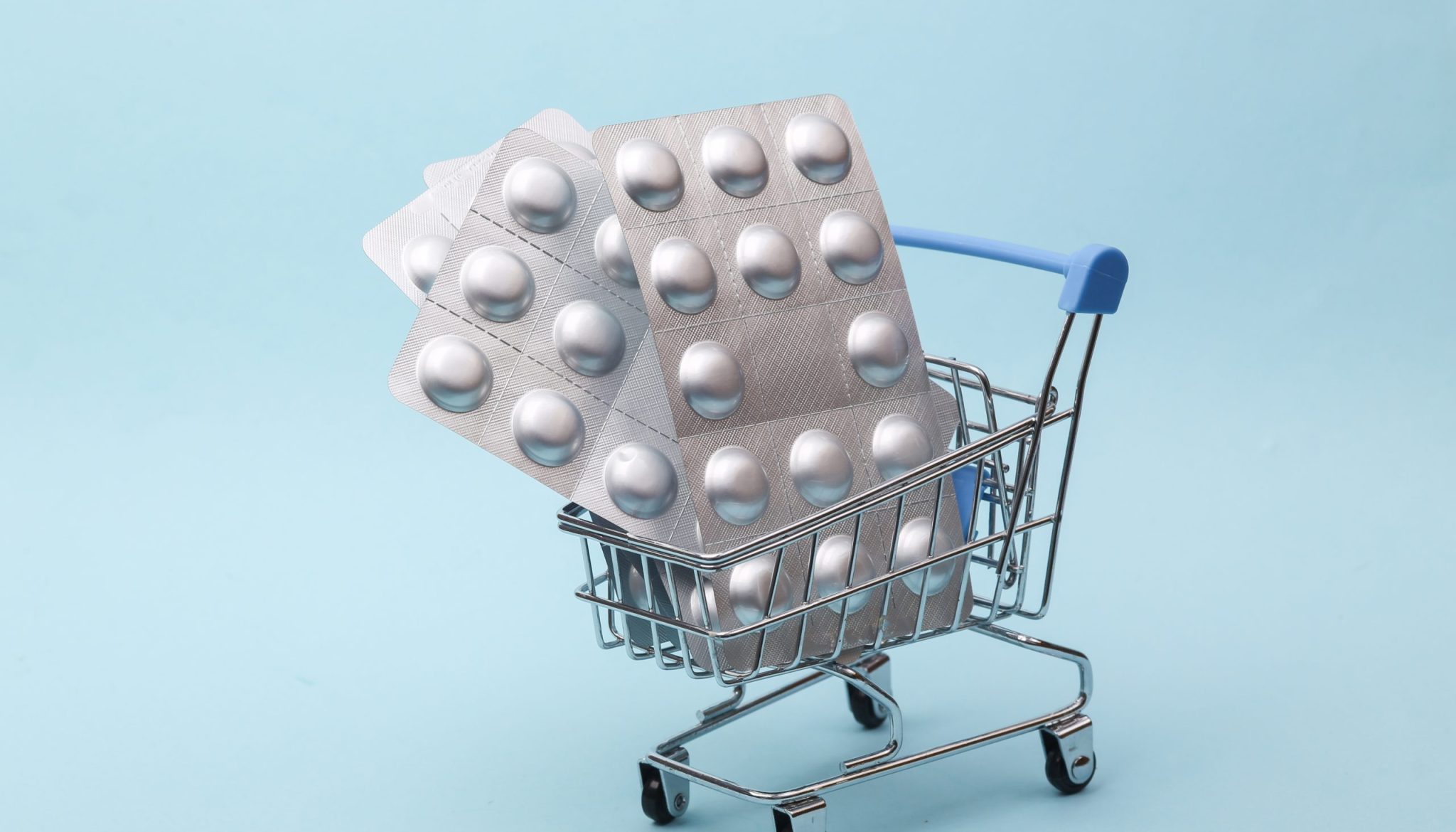 Metal blisters pills in shopping trolley on white background