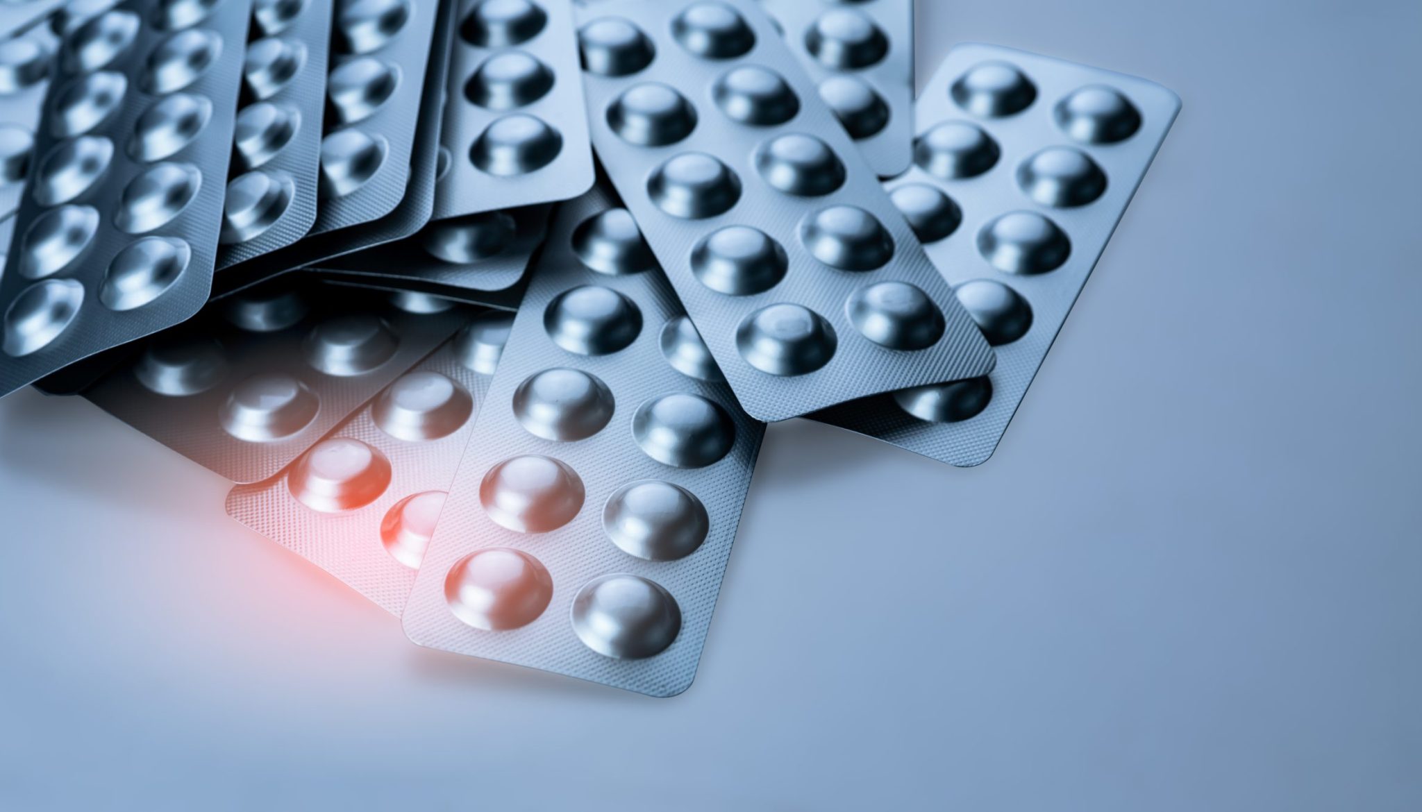 Pile of tablets pill in blister packaging to protect medicine from light. Silver aluminium foil blister pack. Pharmaceutical industry. Pharmacy products. Drug recall and withdrawal from market concept